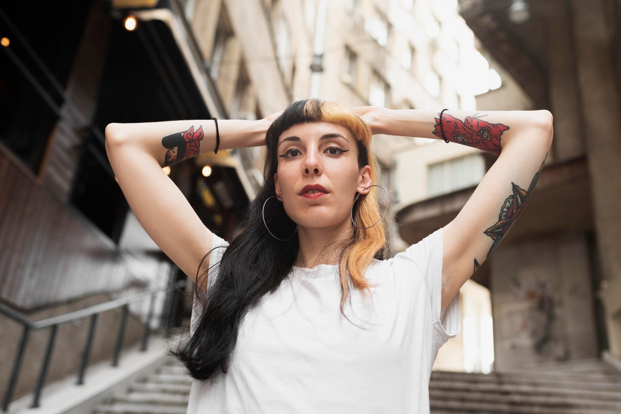 Woman with tattoos on her arms standing in an urban setting